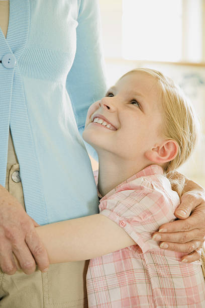 Daughter looking up to mother while holding waist