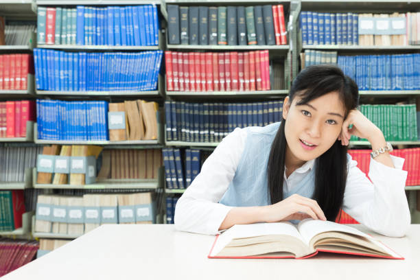istock Asian student reading book in library at university. 638307864