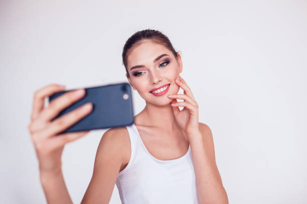 istock Beautiful brunette girl with makeup make selfie on white background. 638321520