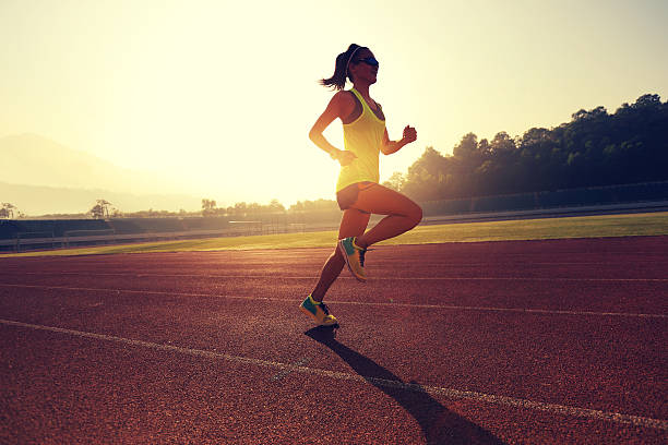 istock Young woman running during sunny morning on stadium track 638325108