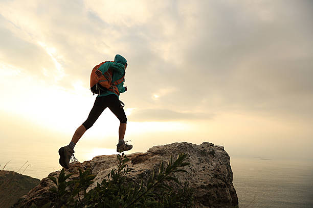 istock successful hiker running on seaside mountain peak rock 638325738