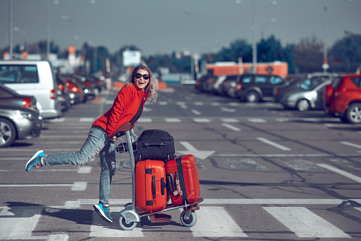 lifestyle shot of happy woman carrying her luggages, laughing and feeling great in her vacation.