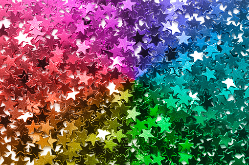 Colorful sparkling star shaped confetti closeup as a background