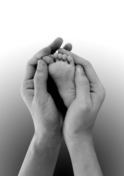 istock Baby's feet in mothers hands on black and white. 638336310