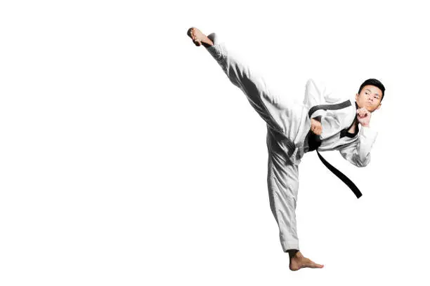 Portrait of a handsome asian man kick with taekwondo black belt . Isolated on white background with copy space