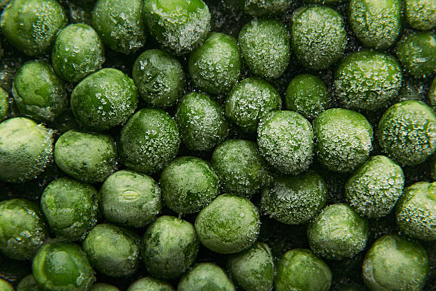 Fresh frozen green peas with hoarfrost closeup as background.