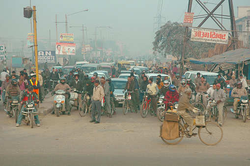 New Delhi, India - January 6, 2007: Early in the morning, pedestrians, automobiles, motorbikes, bicycles waiting at a crossroad before moving on.