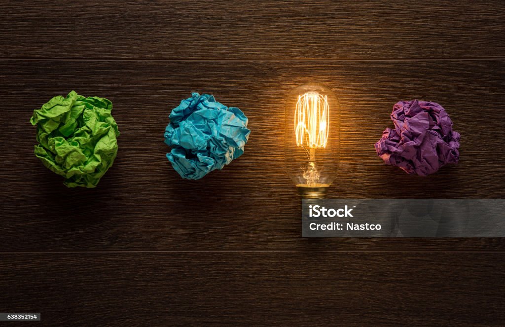 Great idea concept Shining light bulb between crumpled paper sheets with copy space Intellectual Property Stock Photo