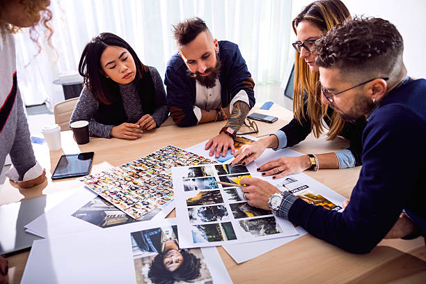 New faces to advertise our brand new product New Business office team at work together on tasks choosing the right image to use in a campaign. editor photos stock pictures, royalty-free photos & images