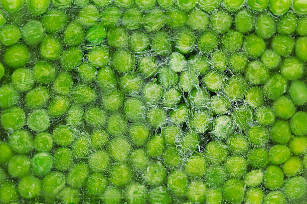 Fresh frozen green peas with hoarfrost closeup as background.