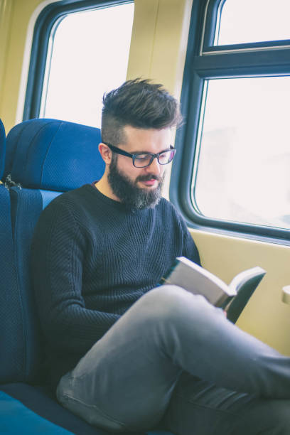 istock Young bearded man sitting in the train and reading 638361436
