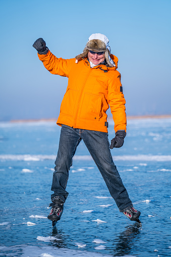senior man looking clumsy while ice skating on frozen lake exercising for his fitness