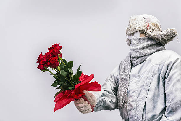 istock Frozen man presenting a bouquet of  a dozen red roses 638363090