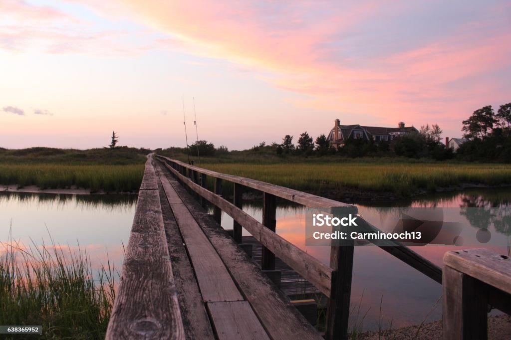 Sunset in The Hamptons Narrow walking bridge running across a creek leading out to the Peconic Bay during sunset in Southampton, NY.  Southampton - New York Stock Photo