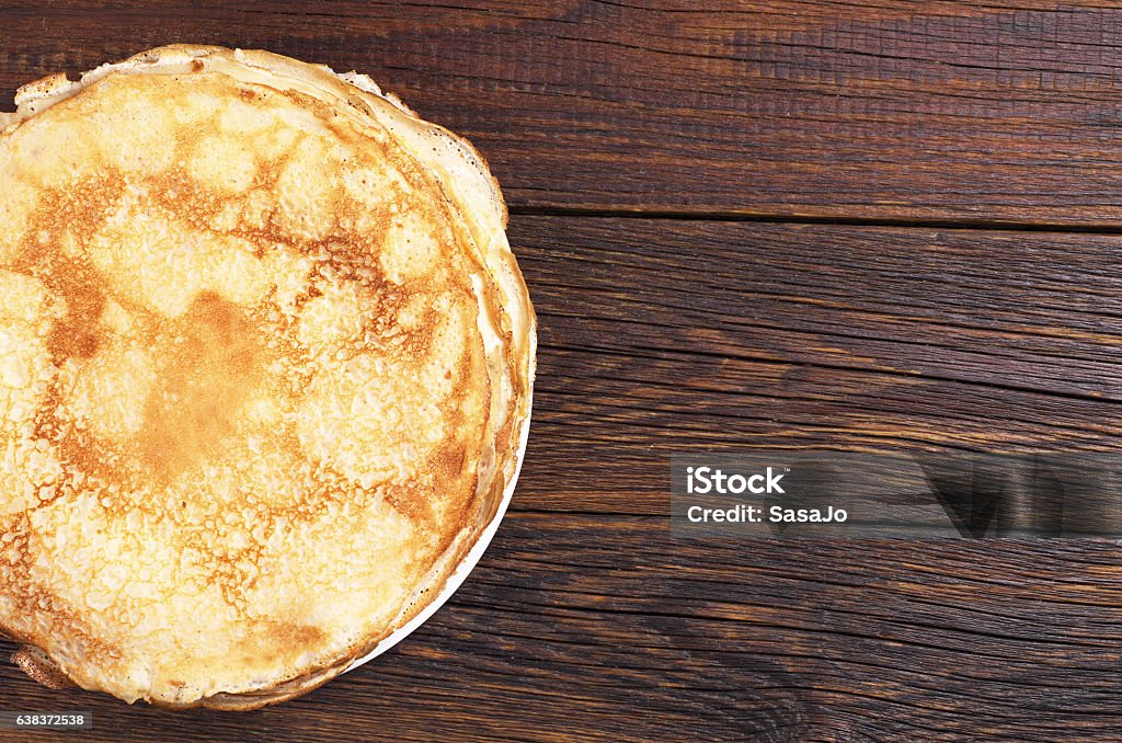 Homemade fried pancake Homemade fried pancake in plate on dark wooden background, top view. Space for text Crêpe - Pancake Stock Photo