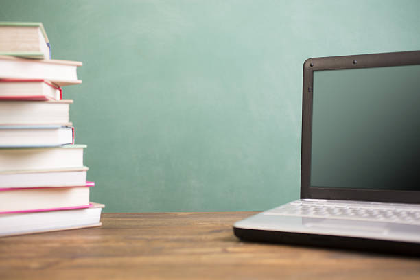 istock Laptop computer and books on school desk with chalkboard. 638372560