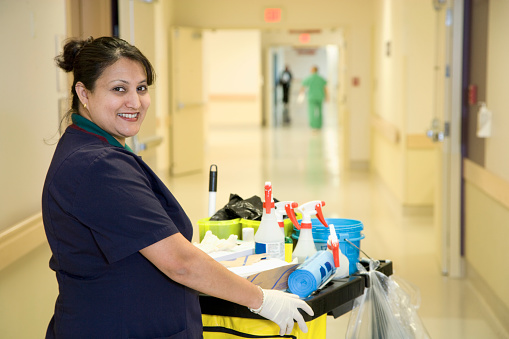Custodian janitor in hospital hallway with cart