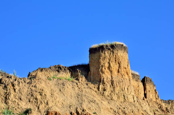 Deep sandy cliff on the background of blue sky. Deep sandy cliff on the background of blue sky. The destruction of the coast as a consequence of soil erosion. odessa beach stock pictures, royalty-free photos & images