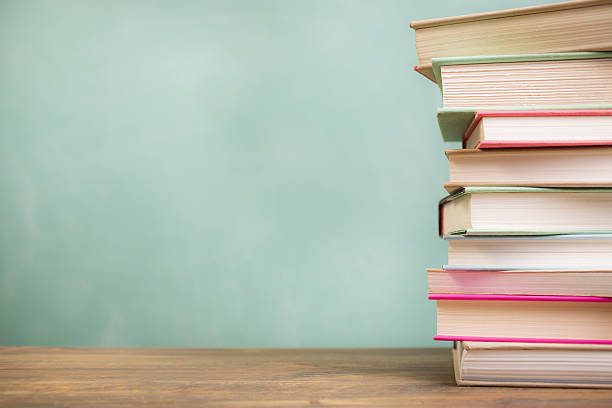 Textbooks stacked on school desk with chalkboard background. stock photo