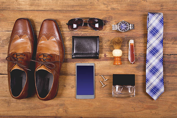Men's accessories organized on table in knolling arrangement Variety of men's accessories organized in knolling arrangement.  Items include: dress shoes, tie, sunglasses, wallet, watch, shaving brush, cologne, and smart phone.  The items all lie on a wooden desk or table.   Men's personal accessories, clothing themes.  Father's Day.  Fashion.  Business.  Retail. wallet photos stock pictures, royalty-free photos & images