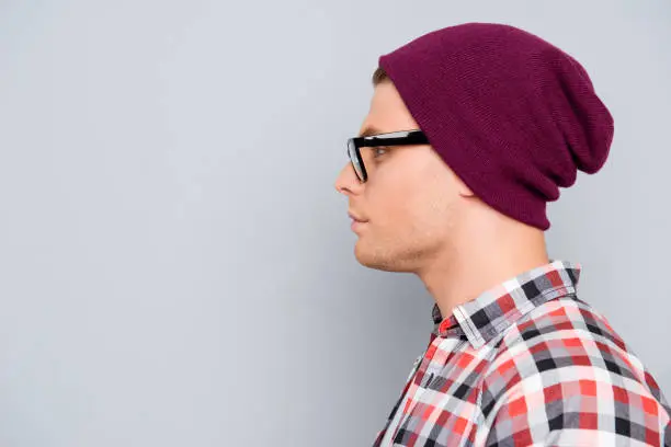 Side view of handsome confident hipster man in violet cap and glasses