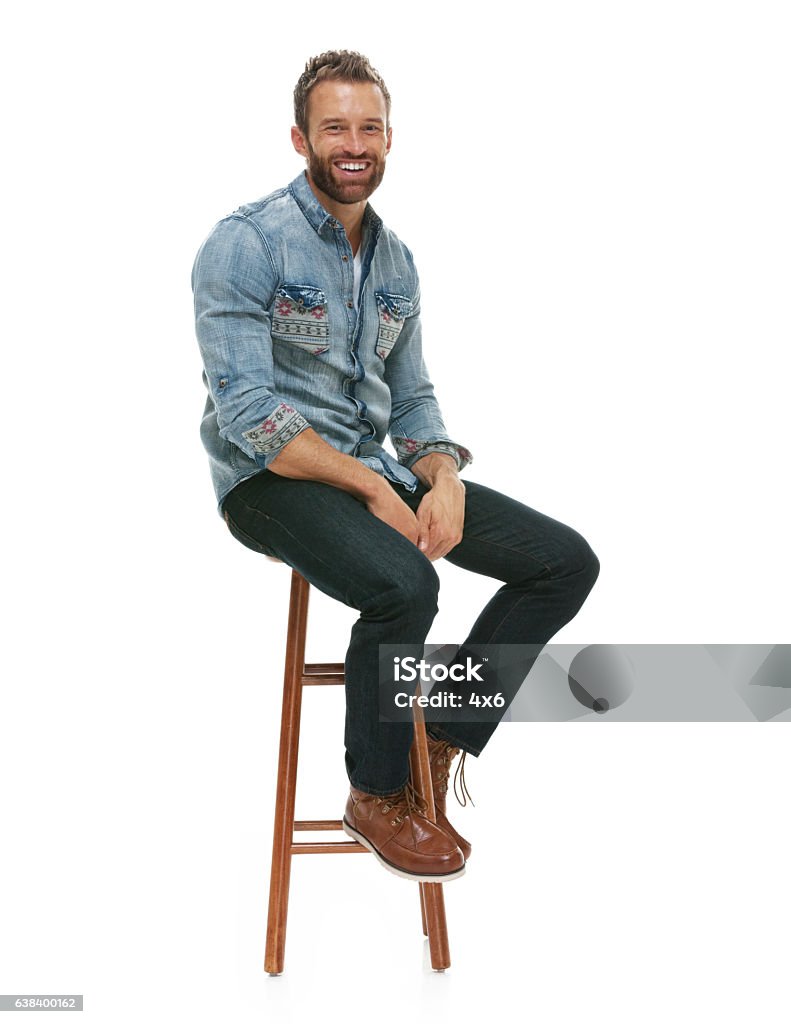 Cheerful man sitting on stool Sitting Stock Photo