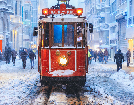 Nostalgic Trams with light passing through Istiklal street in a snowy winter evening in Taksim, Beyoğlu, Istanbul, Turkey.
