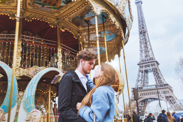 happy couple in Paris, romantic honeymoon near Eiffel tower happy couple in Paris, romantic kiss near carousel and Eiffel tower paris france eiffel tower love kissing stock pictures, royalty-free photos & images