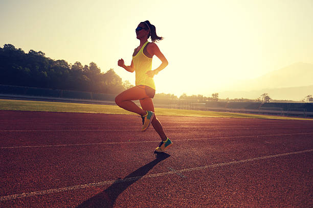 istock Young woman running during sunny morning on stadium track 638412676