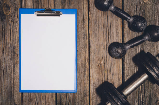 istock Workout plan background. Dumbbells on wooden gym floor or table 638414048