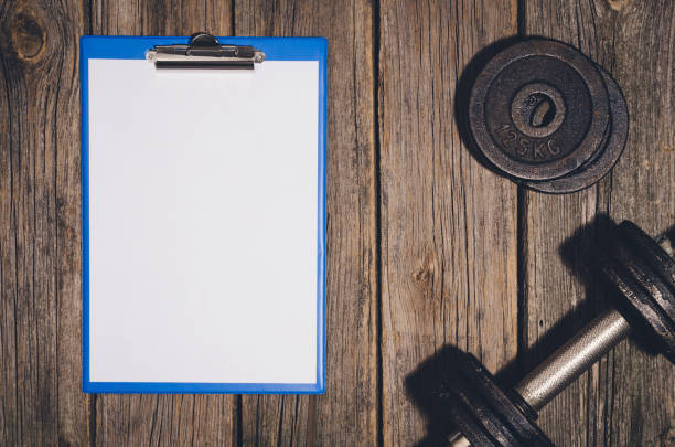 istock Workout plan background. Dumbbells on wooden gym floor or table 638414108