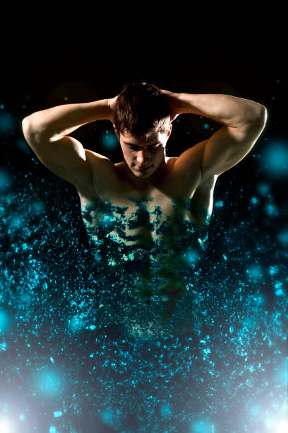 Young mans' body made of blue particles flying around him on black background.