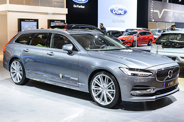 Brussels, Belgium - January 13, 2017: Volvo V90 luxury estate car front view. The Volvo V90 is available as stationwagon and as executive sedan, called S90. The car is displayed on a motor show stand, with lights reflecting off of the body. There are people looking around and other cars on display in the background.