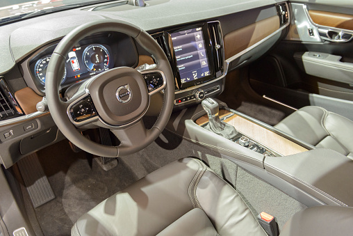 Brussels, Belgium - January 13, 2017: Interior and dashboard on a Volvo V90 luxury estate car. The Volvo V90 is available as stationwagon and as executive sedan, called S90. The V90 is equipped with a large touch screen and electronic dashboard screen. The car is fitted with leather seats and wood details. 