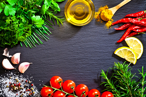 Top view of some cooking and seasoning ingredients shot on dark stone background. Ingredients are placed all around the frame border leaving a useful copy space at the center of the frame.  DSRL studio photo taken with Canon EOS 5D Mk II and Canon EF 100mm f/2.8L Macro IS USM