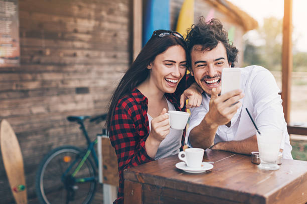 amigos con teléfono inteligente en la cafetería al aire libre - couple outdoors coffee friendship fotografías e imágenes de stock