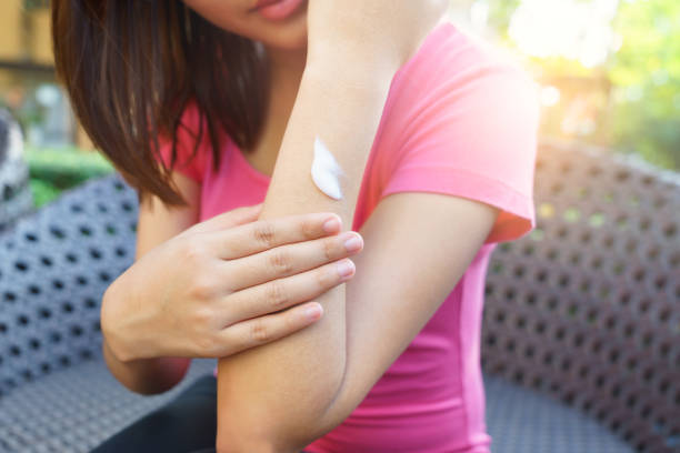 istock Young woman applying body lotion while sitting on chair 638437378