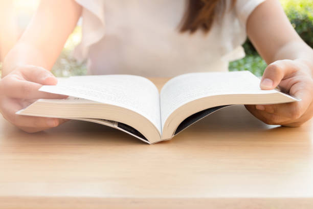 istock Young woman reading a book in the park under sunlight 638437492