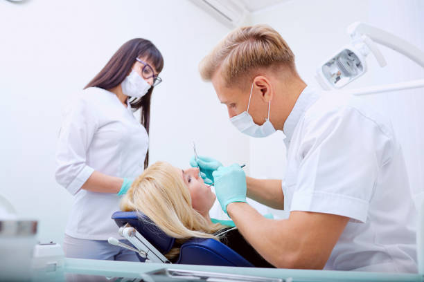 dentiste homme avec assistant traite les dents patient à l’hôpital offi - dental assistent photos et images de collection