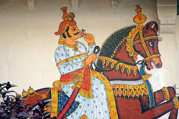 Mural in the City Palace in Udaipur. Mural or wall painting inside the famous City Palace, a complex situated in the city of Udaipur, Rajasthan. It was built over a period of nearly 400 years, with contributions from several rulers of the Mewar dynasty. Construction began in 1553, started by Maharana Udai Singh II of the Sisodia Rajput family as he shifted his capital from the erstwhile Chittor to the new found city of Udaipur. The palace is located on the east bank of Lake Pichola and has several palaces built within its complex. mughal empire stock pictures, royalty-free photos & images