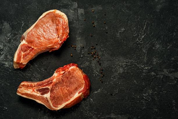 istock Two raw pork steak on a dark black background 638452524