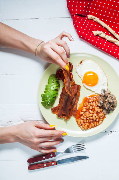 istock Female hands and English breakfast on white wood table 638458772