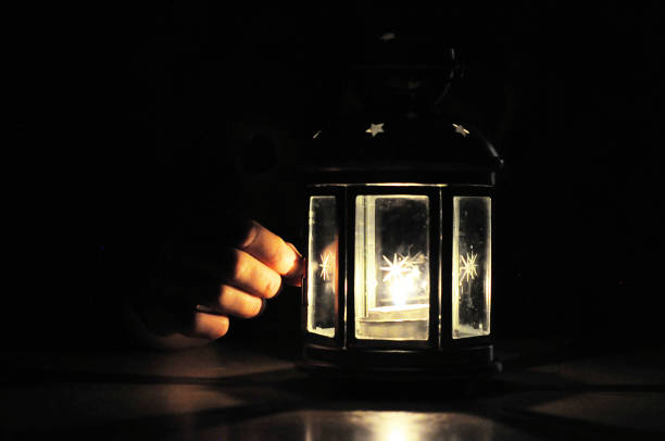 istock Fingers illuminated wirt light from candle lantern in dark, blac 638465570