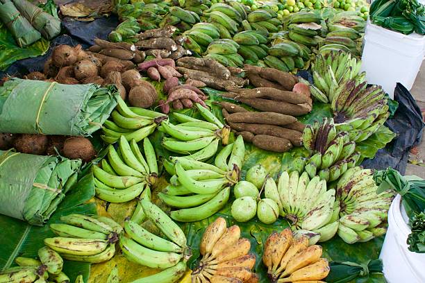View of bright coloured tropical fruit displayed on leaves on the ground at Gizo market Solomon islands.