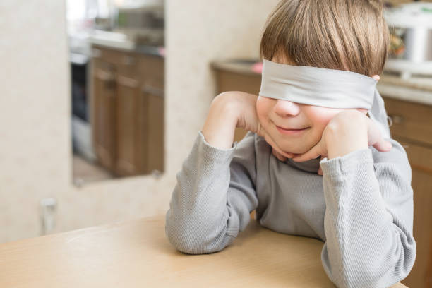 el niño tenía los ojos vendados en casa - venda de ojos fotografías e imágenes de stock