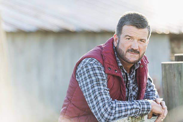 istock Man outside barn leaning on wooden fence 638469370