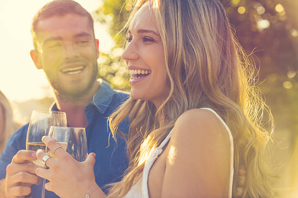 Couple on a date at as restaurant. Couple on a date at as restaurant. There is food and wine on the table. They are happy and laughing. Outdoors at sunset. flirty stock pictures, royalty-free photos & images