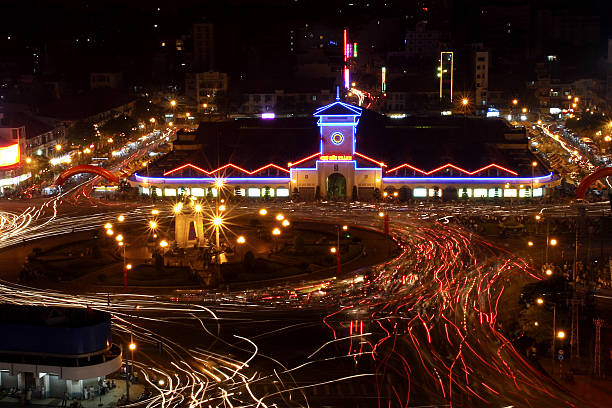 Saigon, market, night, long exposure: Night-time view looking down on Saigon’s famous Ben Thanh market and busy roundabout and side streets.  In the foreground the statue of a mounted horseman in the middle of the roundabout is surrounded by traffic chaos.  Elevated view, looking down.  Logos and advertising signs removed.