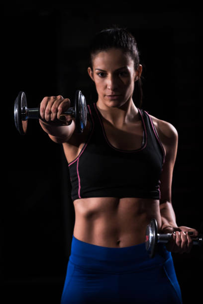 istock Woman bodybuilder  lifting dumbbell isolated over black background 638477548