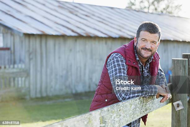 Foto de Homem Do Lado De Fora Do Celeiro Encostado Em Cerca De Madeira e mais fotos de stock de Cena Rural